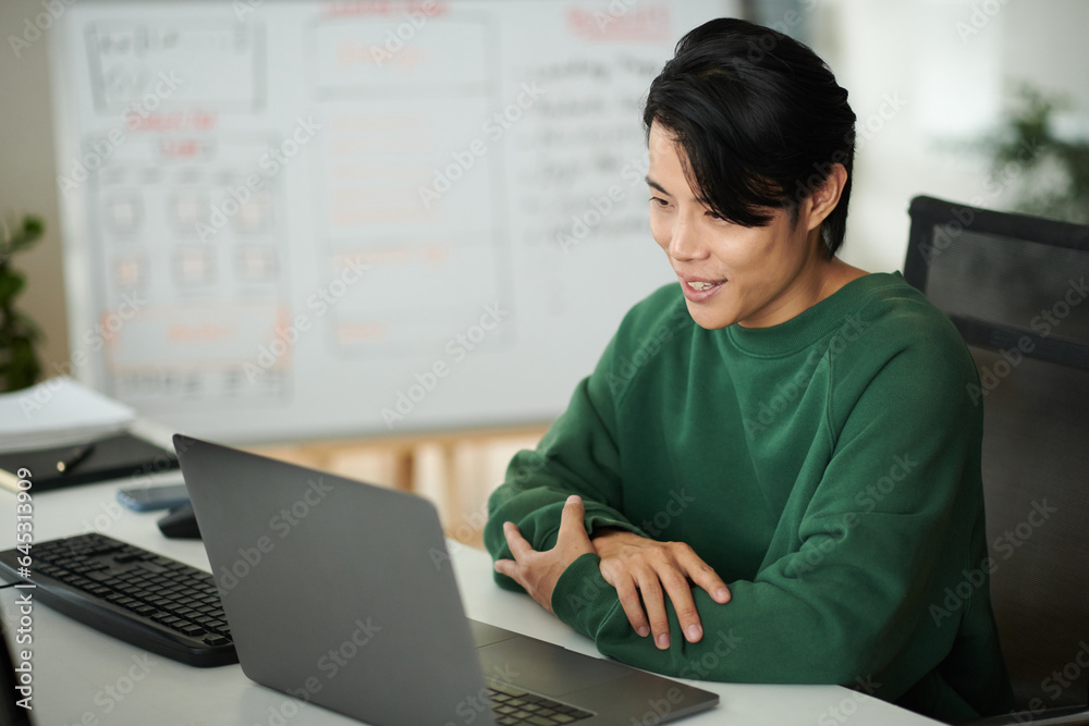 Cheerful programmer discussing details of new application he is working on with team leader in online meeting Cheerful programmer discussing details of new application he is working on with team leader in online meeting
