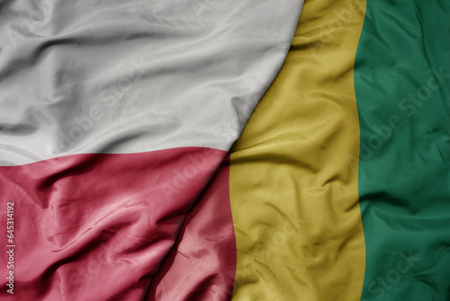 big waving national colorful flag of poland and national flag of guinea .