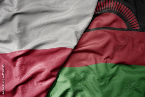 big waving national colorful flag of poland and national flag of malawi .