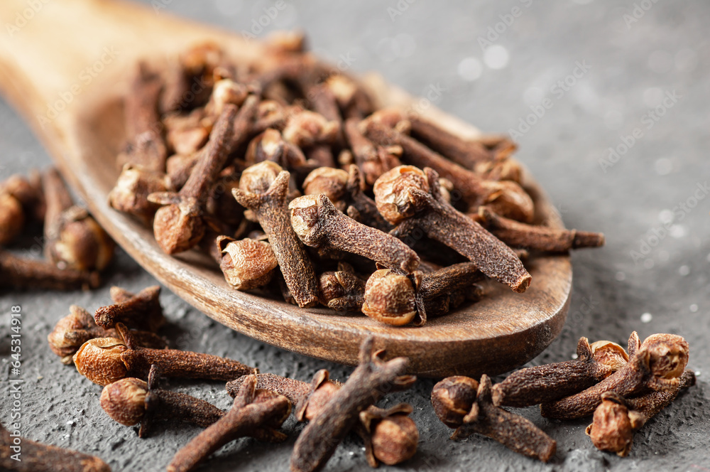 Dry cloves in wooden spoon on rustic table, fresh herb spice concept Dry cloves in wooden spoon on rustic table, fresh herb spice concept