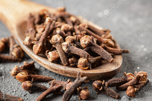 Dry cloves in wooden spoon on rustic table, fresh herb spice concept 