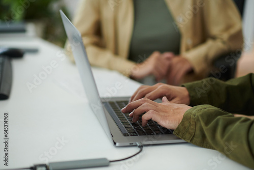 Closeup image of developer working on laptop at office desk