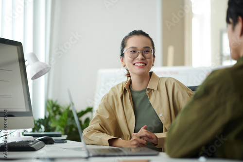 Cheerful young software developer discussing ideas with coworker