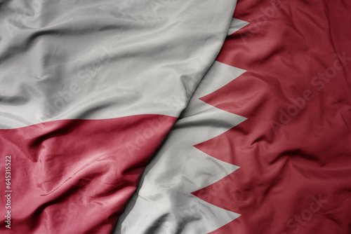 big waving national colorful flag of poland and national flag of bahrain .