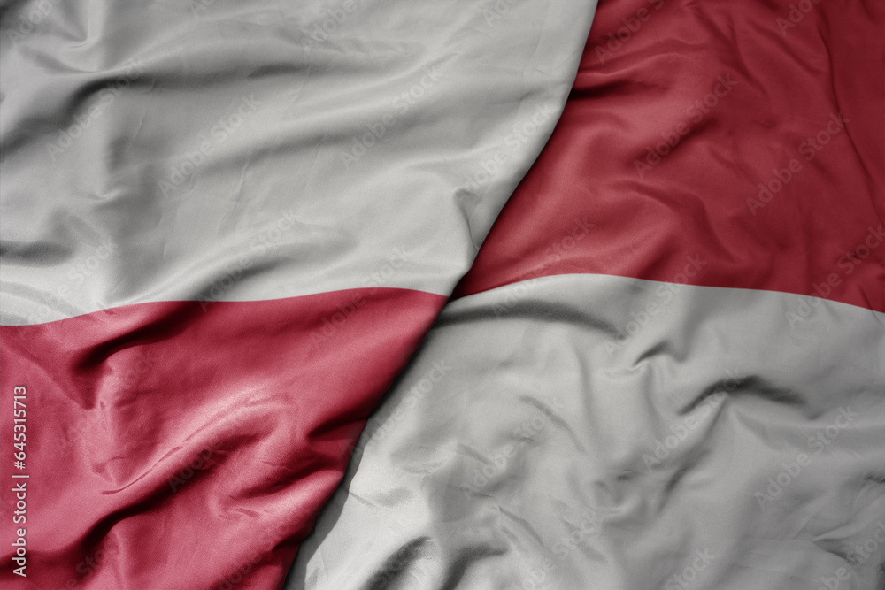 big waving national colorful flag of poland and national flag of indonesia .