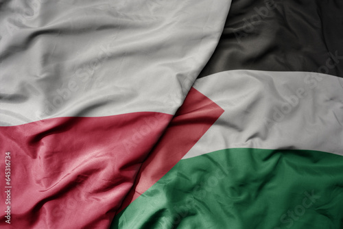big waving national colorful flag of poland and national flag of palestine .