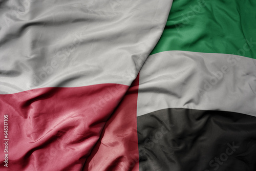 big waving national colorful flag of poland and national flag of united arab emirates .