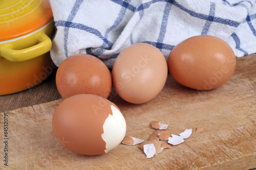 œuf dur en partie épluché en gros plan avec des œufs de poule frais au second plan. photo