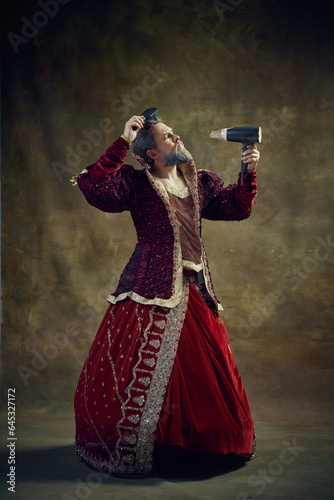 Photography Royal person, king, monarch in female dress doing hairstyle using hair dryer and brush against vintage background