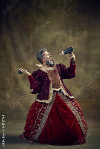 Canvas Print Gray-haired king, monarch in female dress singing in hair dryer while doing hairstyle against vintage background