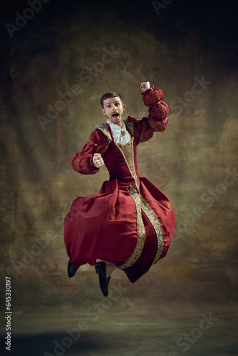 Canvas Print Young emotional man, medieval royal person, prince emotionally jumping in female dress against vintage background