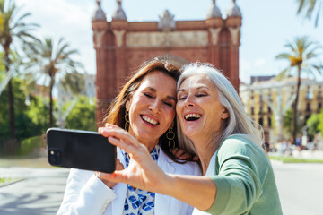 Beautiful senior women meeting outdoors in the city - Two mature female adults friends bonding and having fun while shopping outdoors