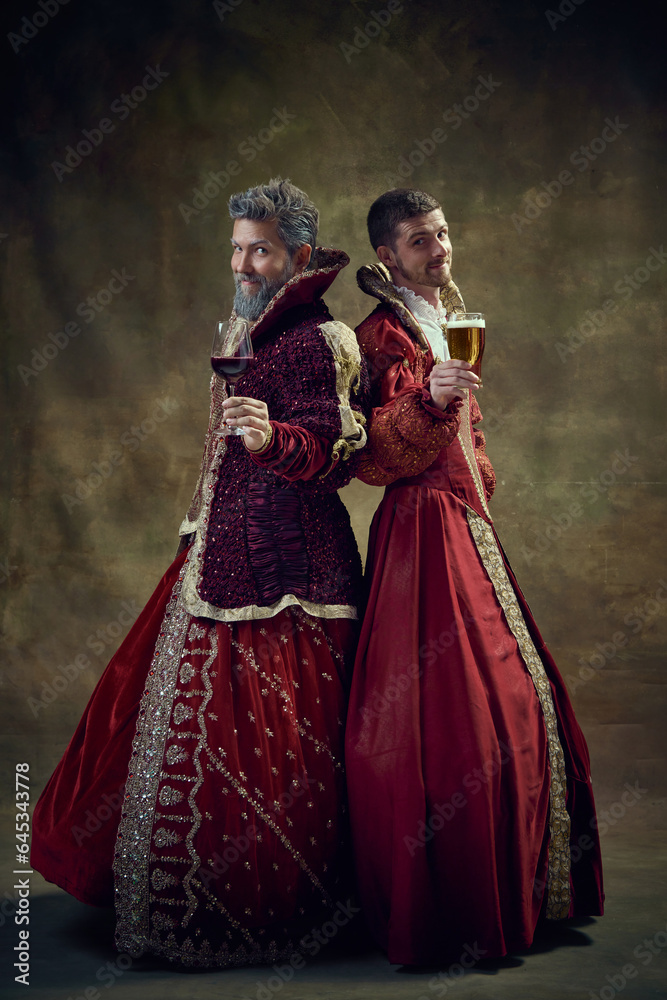 Wine or beer. Renaissance. Royale persons in female dresses standing with glass of wine and beer over dark green background. Concept of historical retrospectives, fashion, provoking projects, alcohol Wine or beer. Renaissance. Royale persons in female dresses standing with glass of wine and beer over dark green background. Concept of historical retrospectives, fashion, provoking projects, alcohol