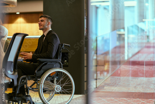 In a modern glass startup office, a wheelchair-bound director leads a successful meeting with colleagues, embodying inclusivity and teamwork.
