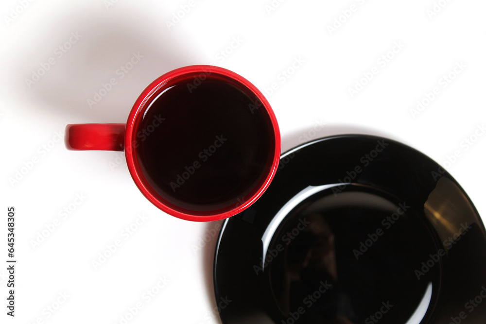 The Red Cup with Tea and the Black Plate on a White Background Top View