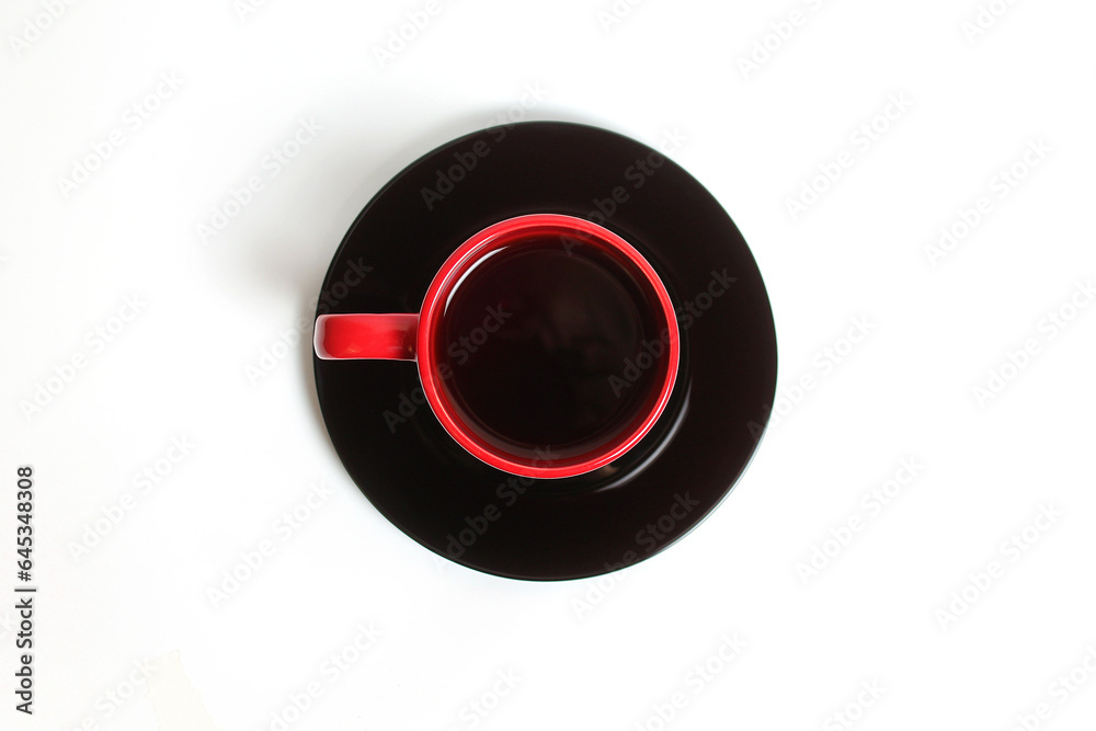The Red Cup with Tea on the Black Plate on a White Background Top View
