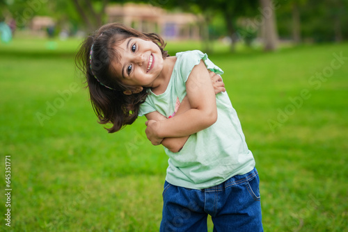 Canvas Print Happy cute little indian girl child standing having fun at summer park or garden
