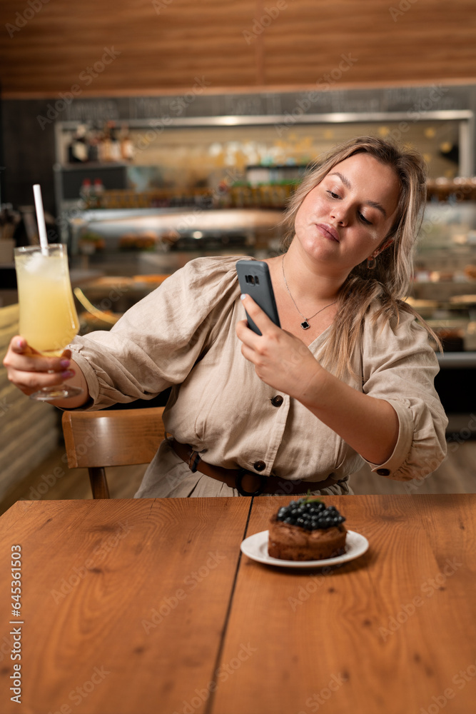 Attractive girl taking cocktail picture with smartphone. Food blogger influencers shooting at restaurant.