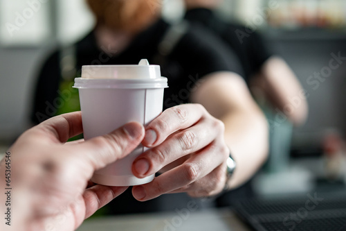 Close up man barista hands gives paper coffee cup
