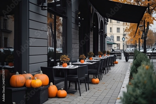 A charming European city street with ancient buildings, street cafes and elegant restaurant tables on a terrace with pumpkins and an autumnal atmosphere.