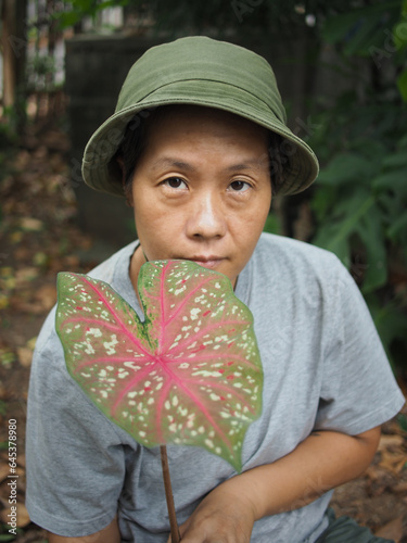 gardenner with colorfull plants in hand and green garden backgrouns happy smile  photo