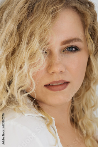 portrait of a young curly happy blonde girl on a white background
