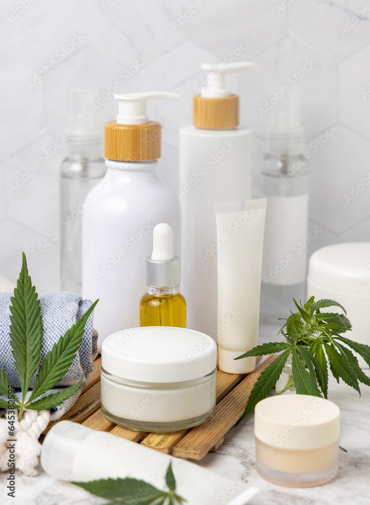 Blank cosmetic jars, tubes and bottles near green cannabis leaves close up, CBD cosmetic mockup Blank cosmetic jars, tubes and bottles near green cannabis leaves close up, CBD cosmetic mockup