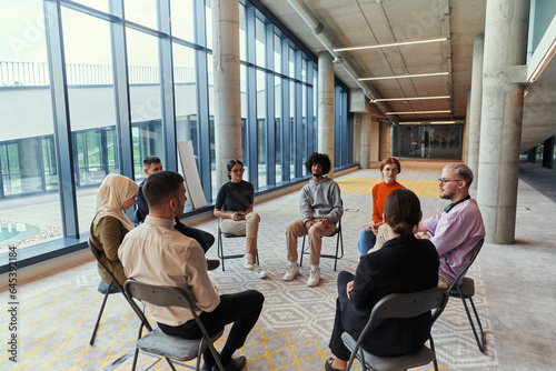 A diverse group of young business entrepreneurs gathered in a circle for a meeting, discussing corporate challenges and innovative solutions within the modern confines of a large corporation