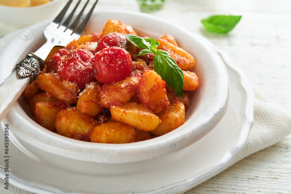 Potato gnocchi. Traditional homemade potato gnocchi with tomato sauce, basil and parmesan cheese on kitchen table on light grey kitchen table background. Traditional Italian food. Top view. Potato gnocchi. Traditional homemade potato gnocchi with tomato sauce, basil and parmesan cheese on kitchen table on light grey kitchen table background. Traditional Italian food. Top view.