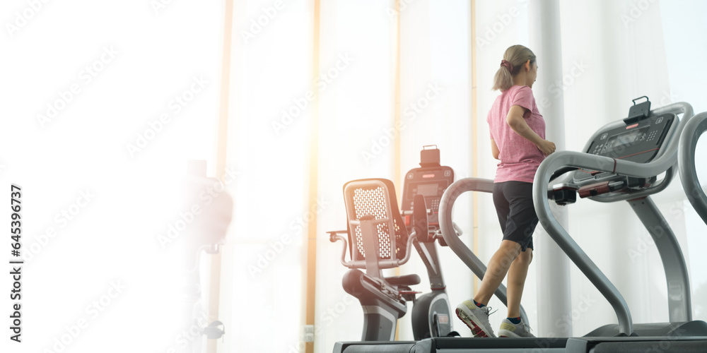 Woman running or jogging in a gym on a treadmill machine concept for exercising, fitness and healthy lifestyle. Close up at foot and shoe. Workout and cardio in sport club.