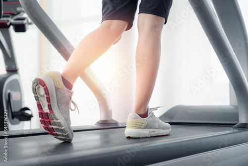 Woman leg running or jogging in a gym on a treadmill machine concept for exercising, fitness and healthy lifestyle. Close up at foot and shoe. Workout and cardio in sport club.