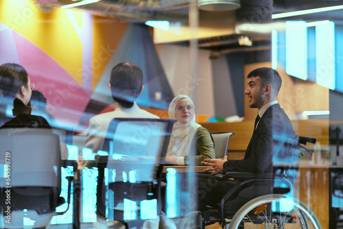 Foto In a modern glass startup office, a wheelchair-bound director leads a successful meeting with colleagues, embodying inclusivity and teamwork