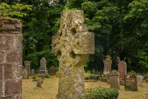 2023-06-04 A OLD STONE CROSS IN A CEMETARY IN NIGG SCOTLAND WITH A GREEN TREE LINED BACKGROUND