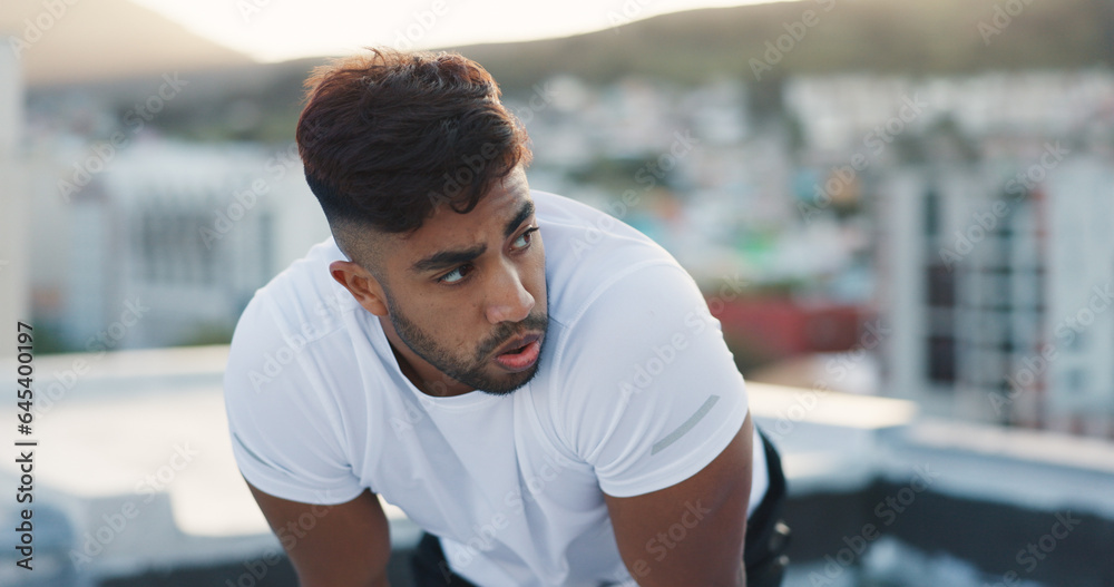 Fototapeta premium Fitness, city and tired man on a rooftop after running training, cardio workout and exercise outdoors. Runner, sports and healthy athlete exhausted with fatigue breathing or resting on a terrace