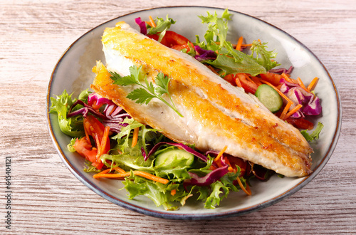 фотографія seabass fish fillet over salad