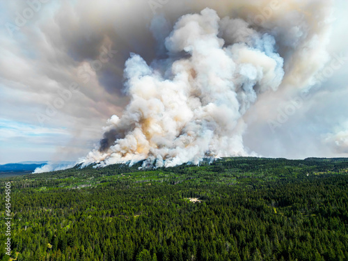 Giant fire in the Canadian forest, top aerial view of a fire in the forest. Ecological catastrophy. Rescue helicopters circle over the gift in the forest. Huge pillars of smoke