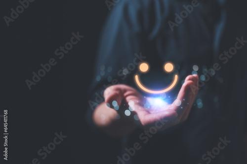 Customer service satisfaction survey concept.Business people or customers show satisfaction by holding face emoticon smile in satisfaction on virtual touch screen. rating very impressed