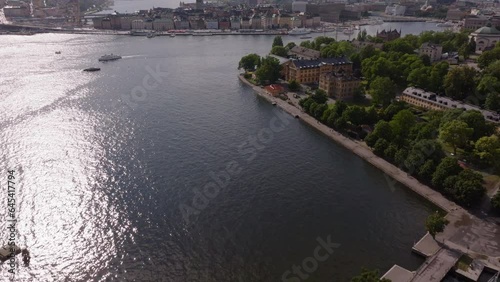 High angle view of waterfront, rippled water surface reflecting sunshine. Tilt up reveal cityscape with sights in old town district on Kvarteret Luna island. Stockholm, Sweden photo