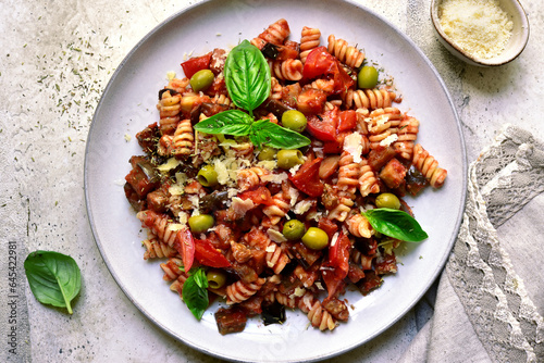 Pasta alla norma, fusilli with eggplants, tomatoes and olives. Traditional dish of sicilian cuisine. Top view with copy space.