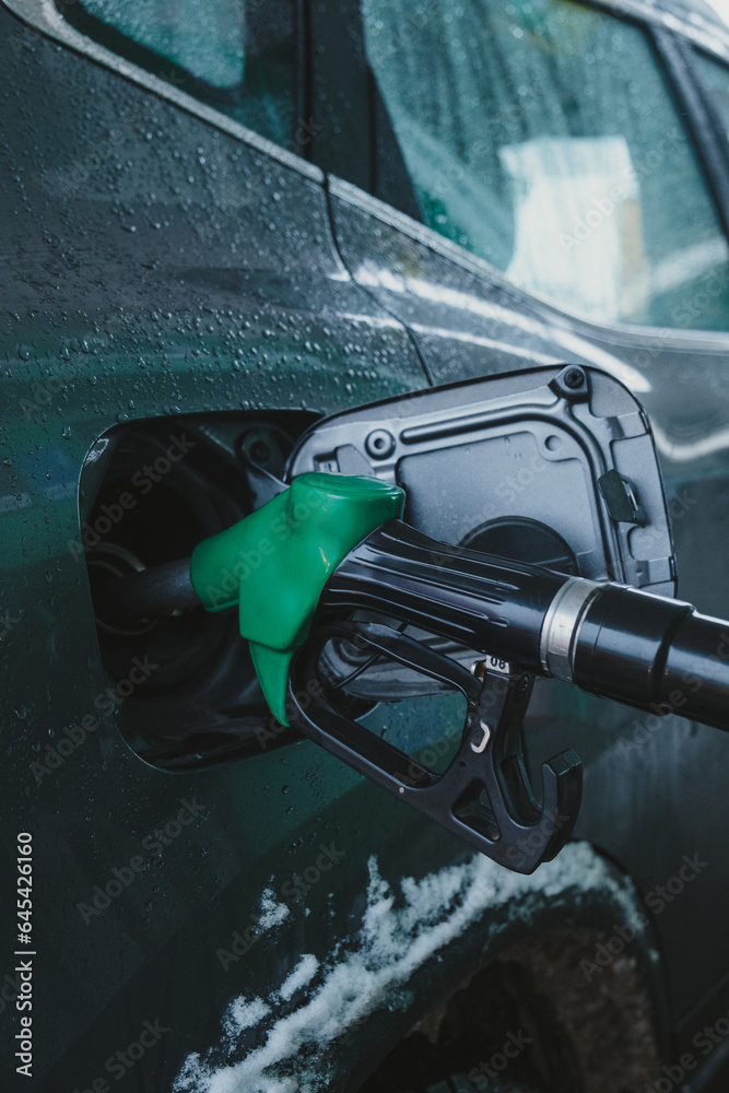 gas pump nozzle in car's fuel tank.