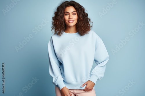 Isolated Portrait of a Fictional Female Model Wearing a Large Oversized Light Blue Colored Sweatshirt on a Plain Blank Background. Generative AI.