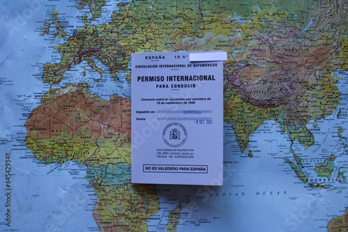 International Spanish Driver's License for travelling and drive around the world. With a world map background.
