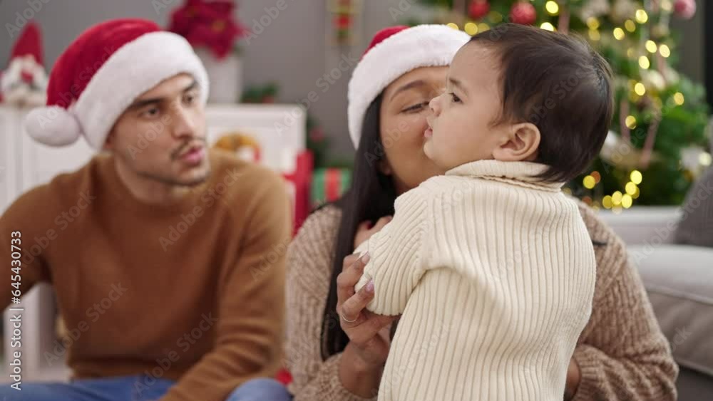 Couple and son holding decoration ball sitting on floor by christmas tree at home Couple and son holding decoration ball sitting on floor by christmas tree at home