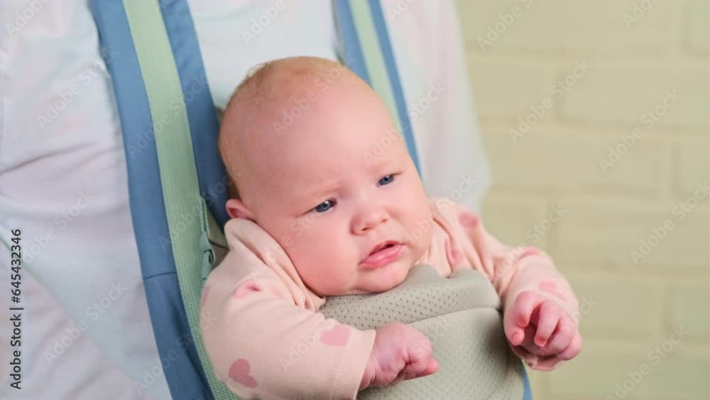 Portrait of a cute little baby girl in a sling looking at the camera. Portrait of a cute little baby girl in a sling looking at the camera.