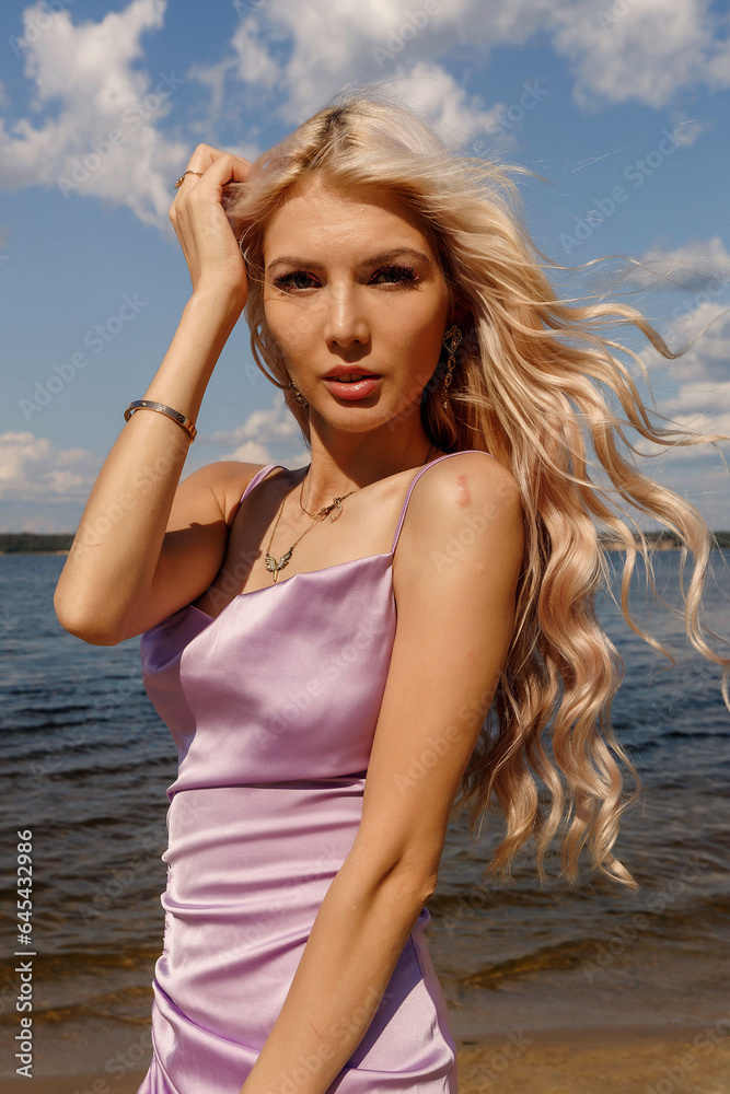 a girl in a purple dress on the bank of a river on a sunny day