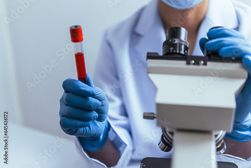 Fototapeta Naklejka Na Ścianę i Meble -  Hands of a doctor or female doctor collecting blood sample tubes from rack with analyzer in lab. Doctor holding blood test tube in research laboratory red blood cells