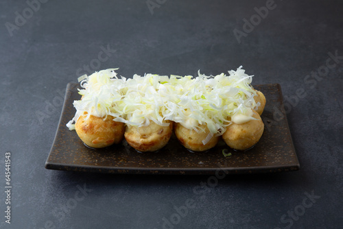 takoyaki with green onions on top of a dark gray background