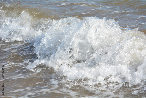 Ocean waves crashing on sandy beach. Sea waves breaking on shore. Nature splash on summer day. Sea wave crashing on beach. Summer holidays concept. Splashing sea water with foam.