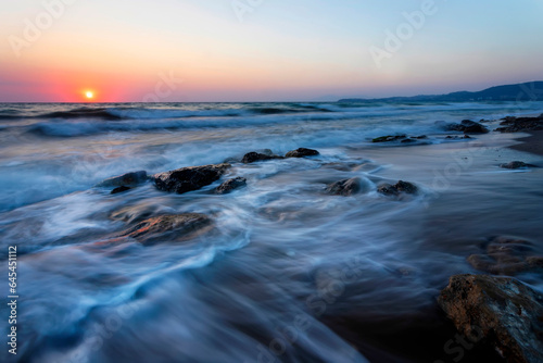 A seascape photographed with a long exposure technique at sunset.