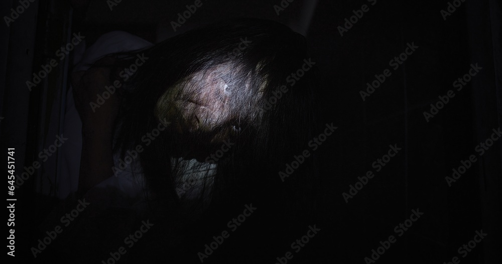 Horror scene of a mysterious Scary closeup eyes Asian ghost woman creepy have hair covering the face looking to camera at abandoned house with background dark scene movie at night, festival Halloween Horror scene of a mysterious Scary closeup eyes Asian ghost woman creepy have hair covering the face looking to camera at abandoned house with background dark scene movie at night, festival Halloween